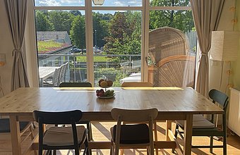 Ausblick aus dem Esszimmer ins Grüne durch eine große Fensterfront 